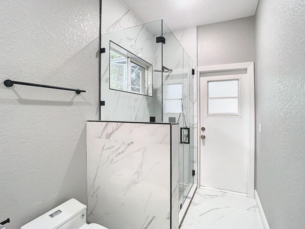 Ducha renovada con paneles claros y puerta de vidrio